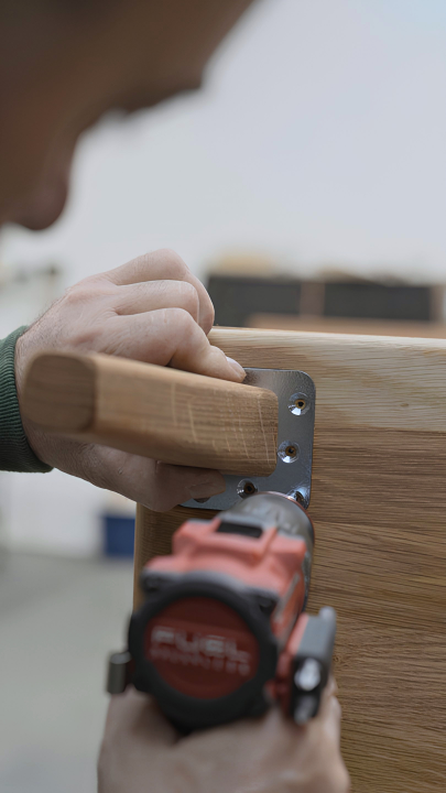 Ein Linea-D-Mitarbeiter befestigt Massivholz-Tischbeine von Hand